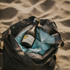 Limoni Spritz Flasche und 2 Weingläser liegen in einer Strandtasche auf Sand
